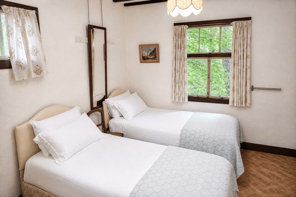 Small twin bedroom with washbasin, overlooking woodland at Windy Gap